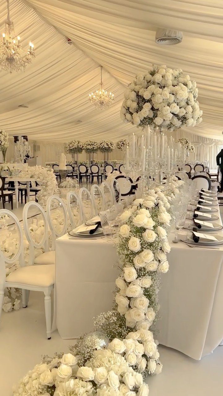 White rose floral centerpieces and draped fabric ceiling at an elegant wedding reception.
