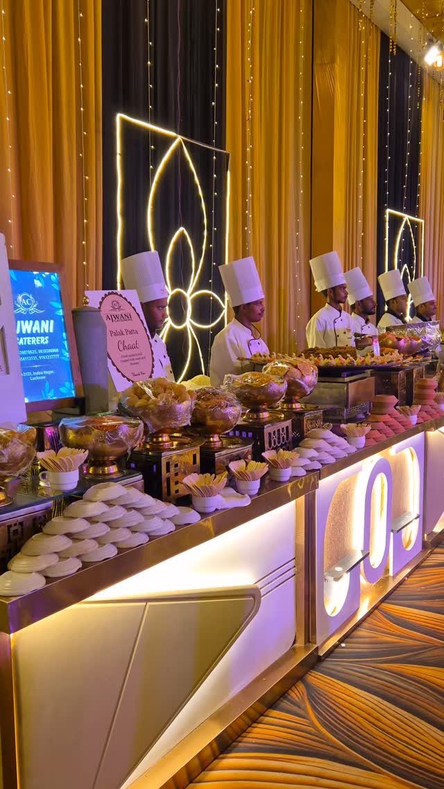 Buffet line with chefs and gold curtains at a large event venue.