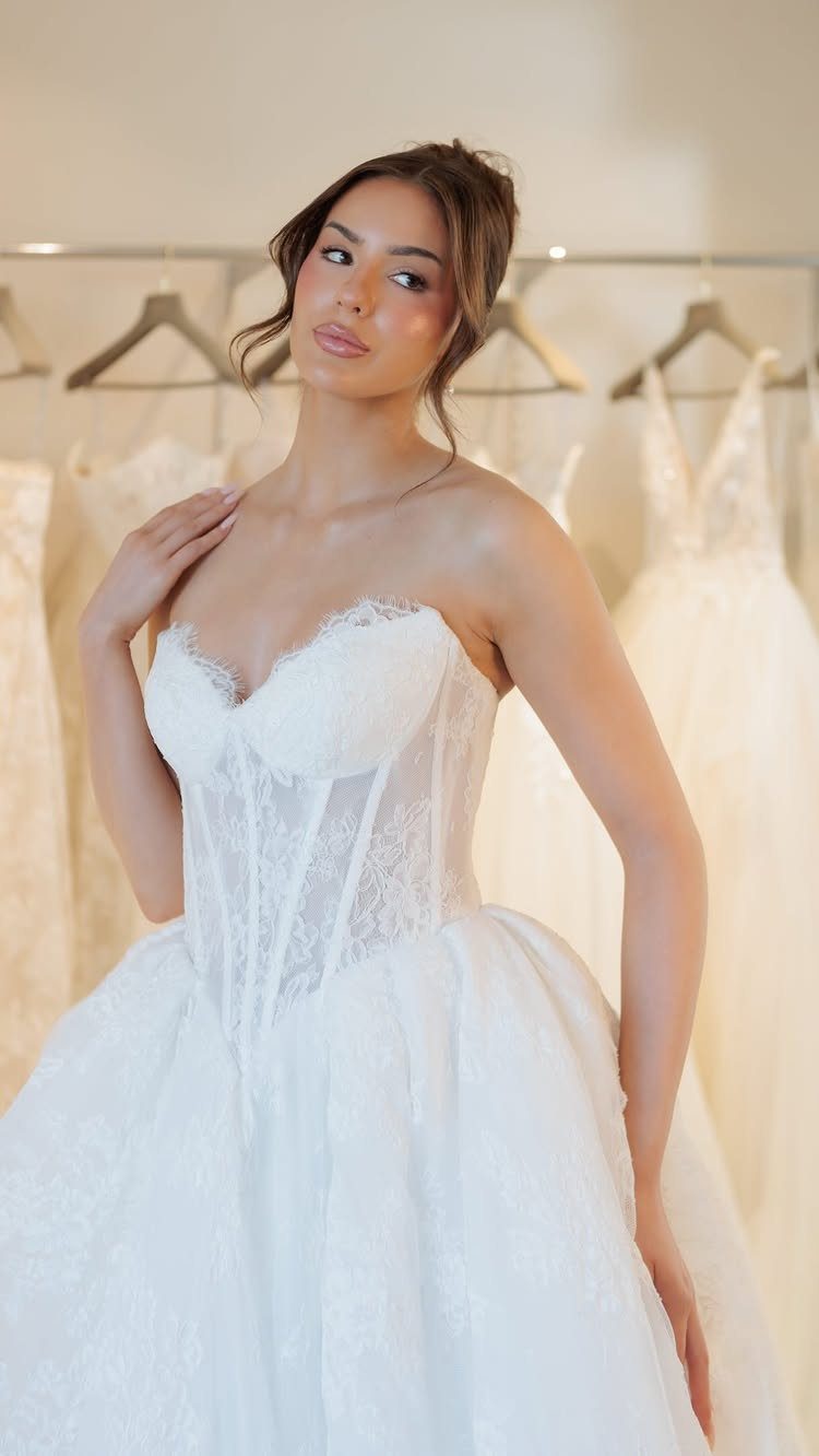 Basque Waist Wedding Dress Lace Ideas: 5 Styles 5 Woman wearing a white lace wedding dress with a basque waist in a bridal shop