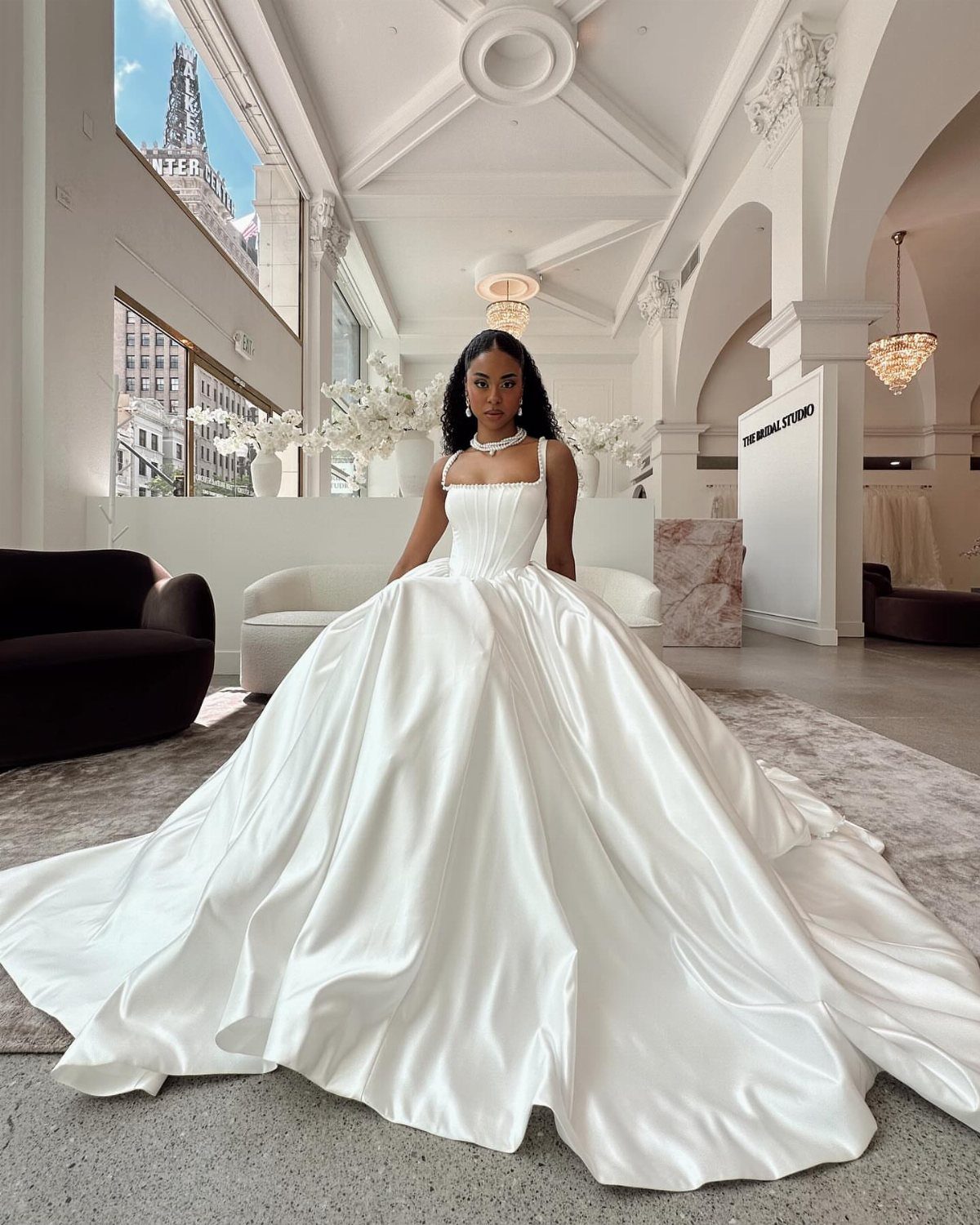6 Basque Wedding Dress Ideas, from Lace to Ball Gowns 3 Woman in a white satin Basque waist ball gown wedding dress in a bright studio.