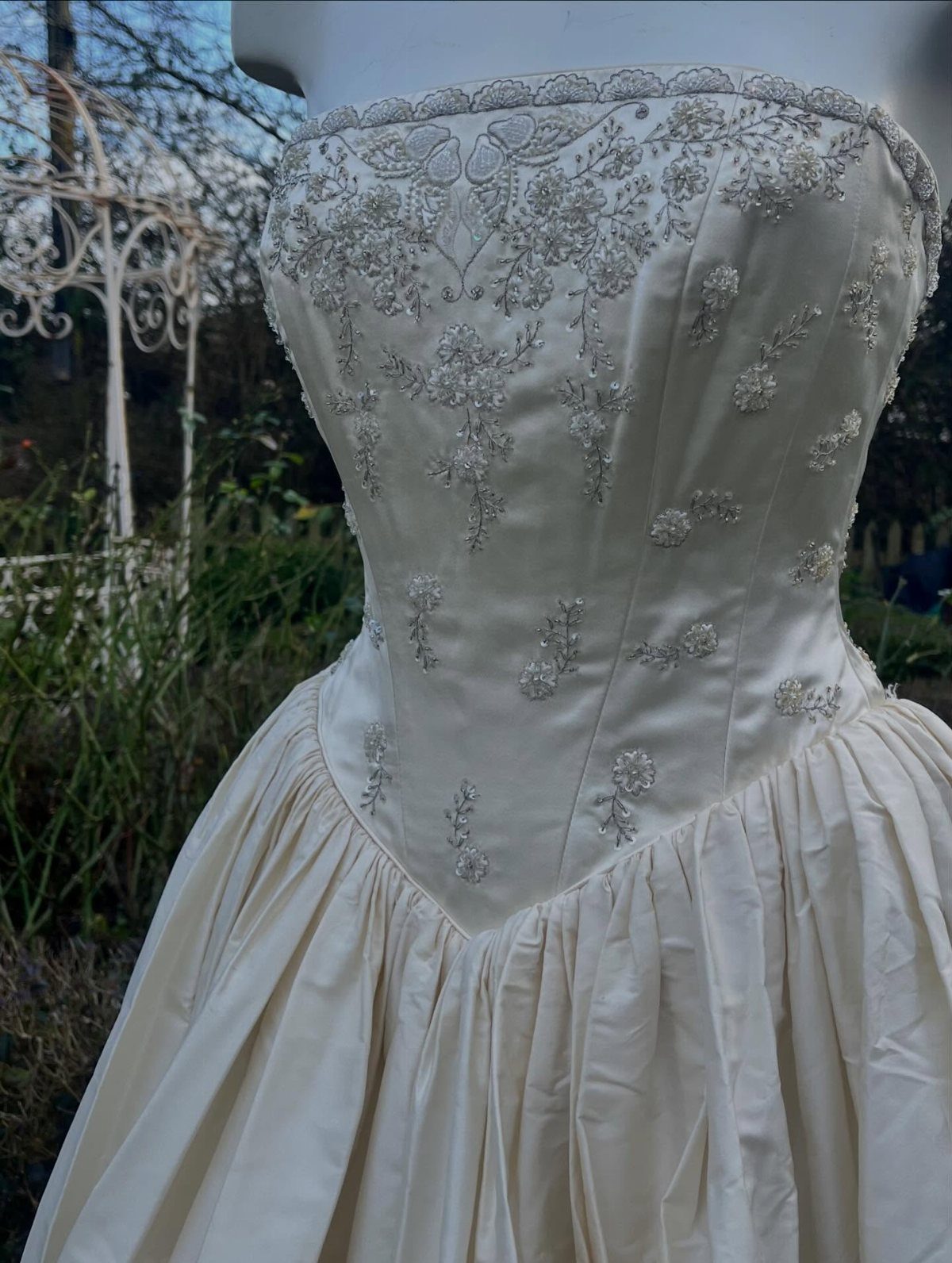 6 Basque Wedding Dress Ideas, from Lace to Ball Gowns 4 Cream wedding dress with beaded Basque waist and full pleated skirt on mannequin.