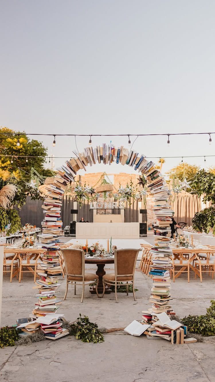 Book archway over a small dining table at an outdoor wedding reception venue