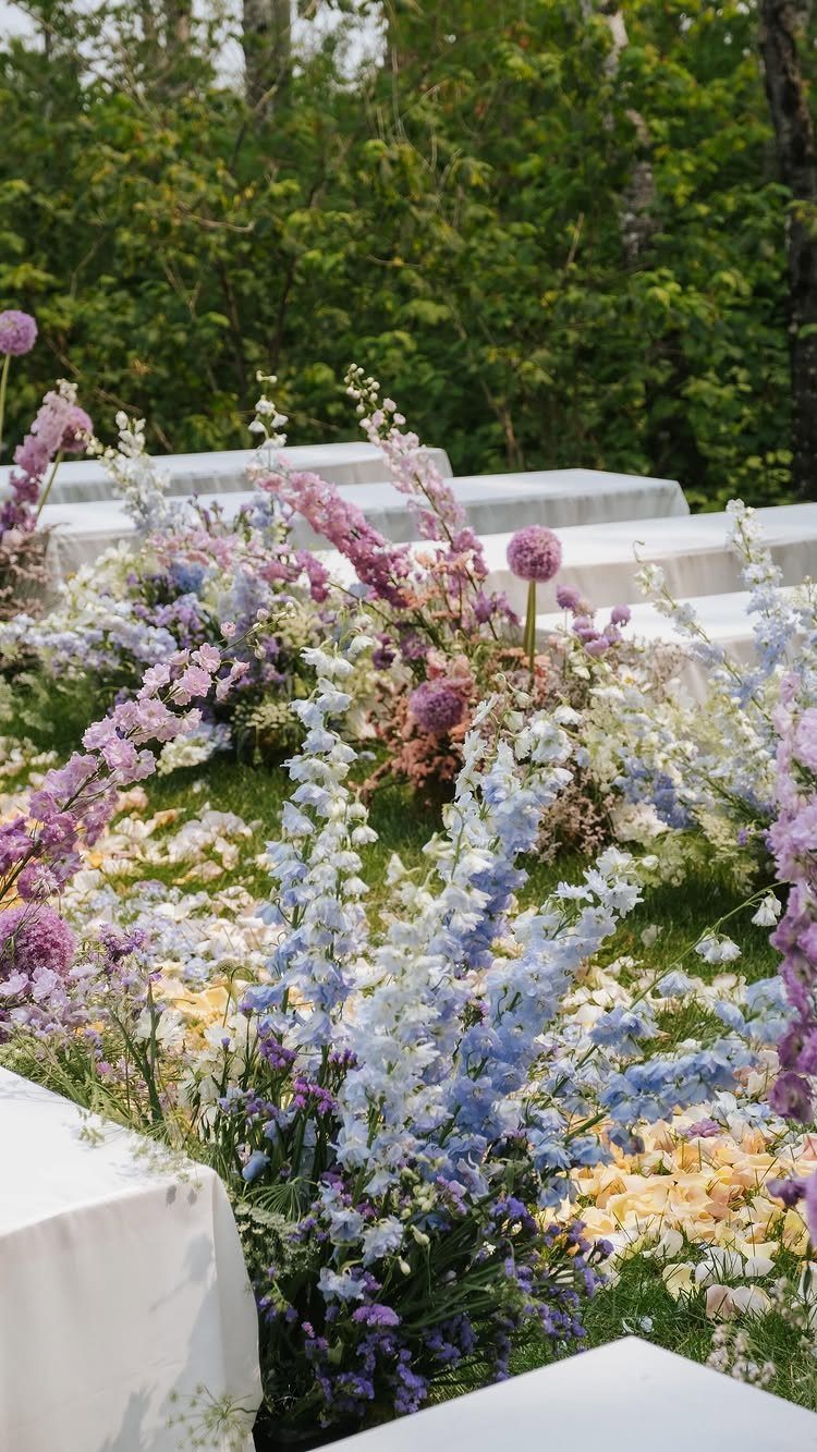 Colorful floral arrangements with blue and purple flowers at an outdoor wedding ceremony