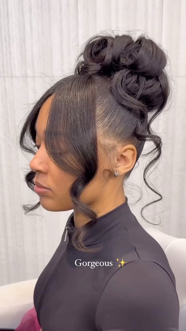 11 Black Natural Hair Wedding Hairstyles for Brides 8 Black woman with a high voluminous bun and curly tendrils in a side profile.