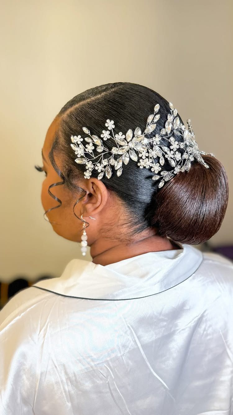 11 Black Natural Hair Wedding Hairstyles for Brides 5 Woman with a sleek low bun and a silver rhinestone floral hair accessory.