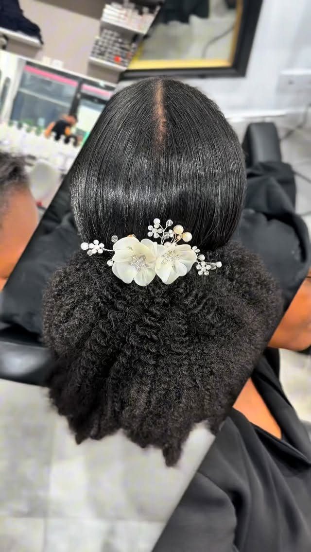 11 Black Natural Hair Wedding Hairstyles for Brides 3 Black natural hair in a low bun adorned with white floral hair accessories.