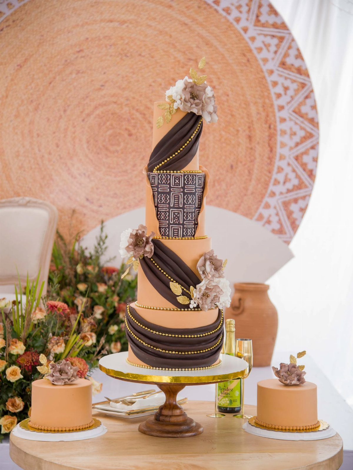 Multi-tiered peach cake with dark brown chocolate swirls and gold beaded accents.