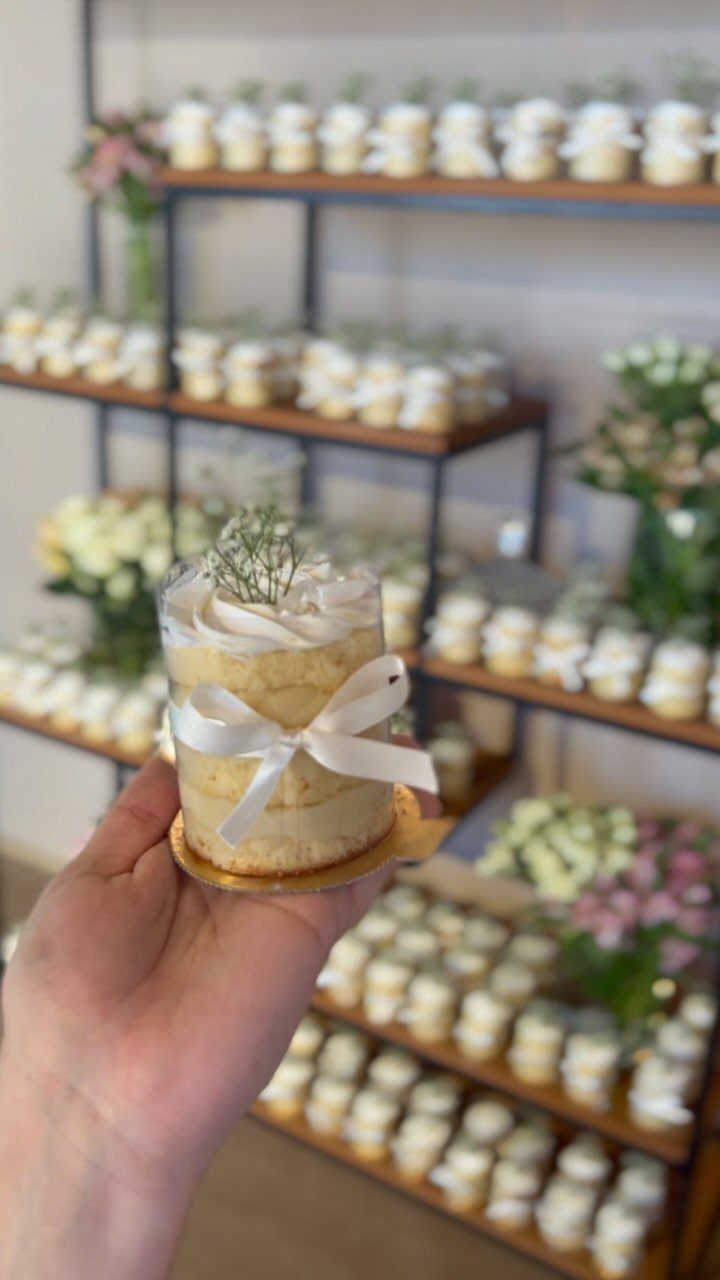 Small individual cake with white ribbon and baby's breath on a gold base.