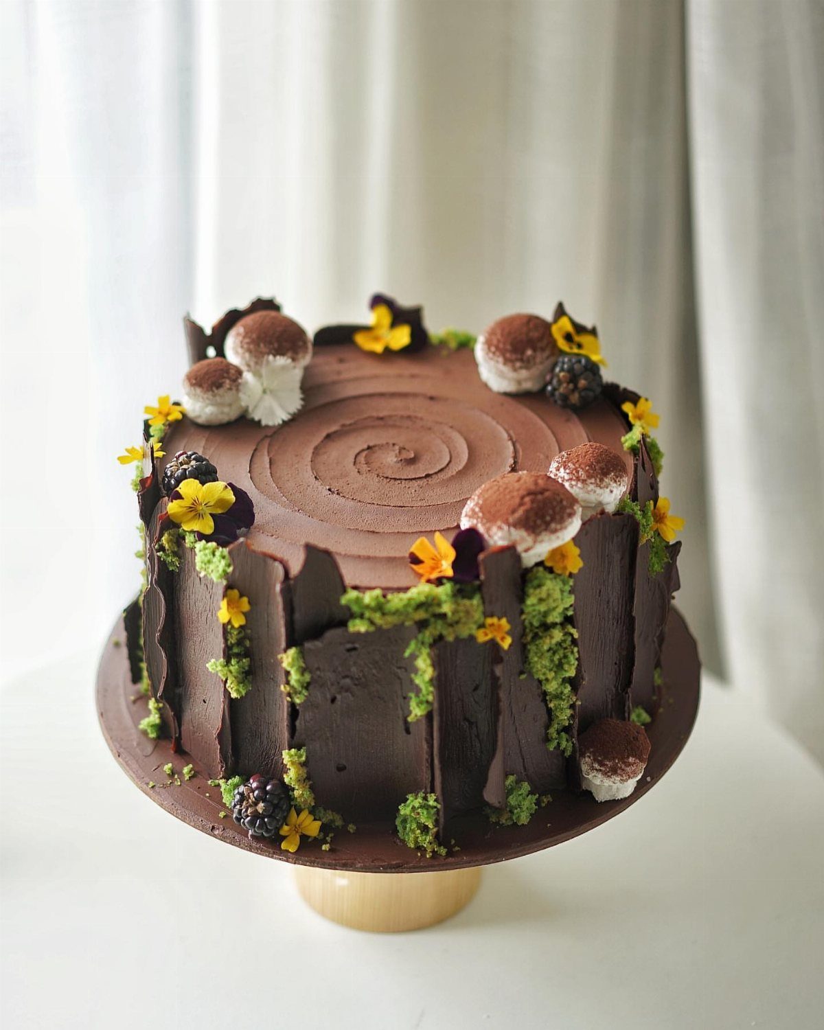 Chocolate cake designed as a rustic wood slice with mushrooms and yellow flowers.