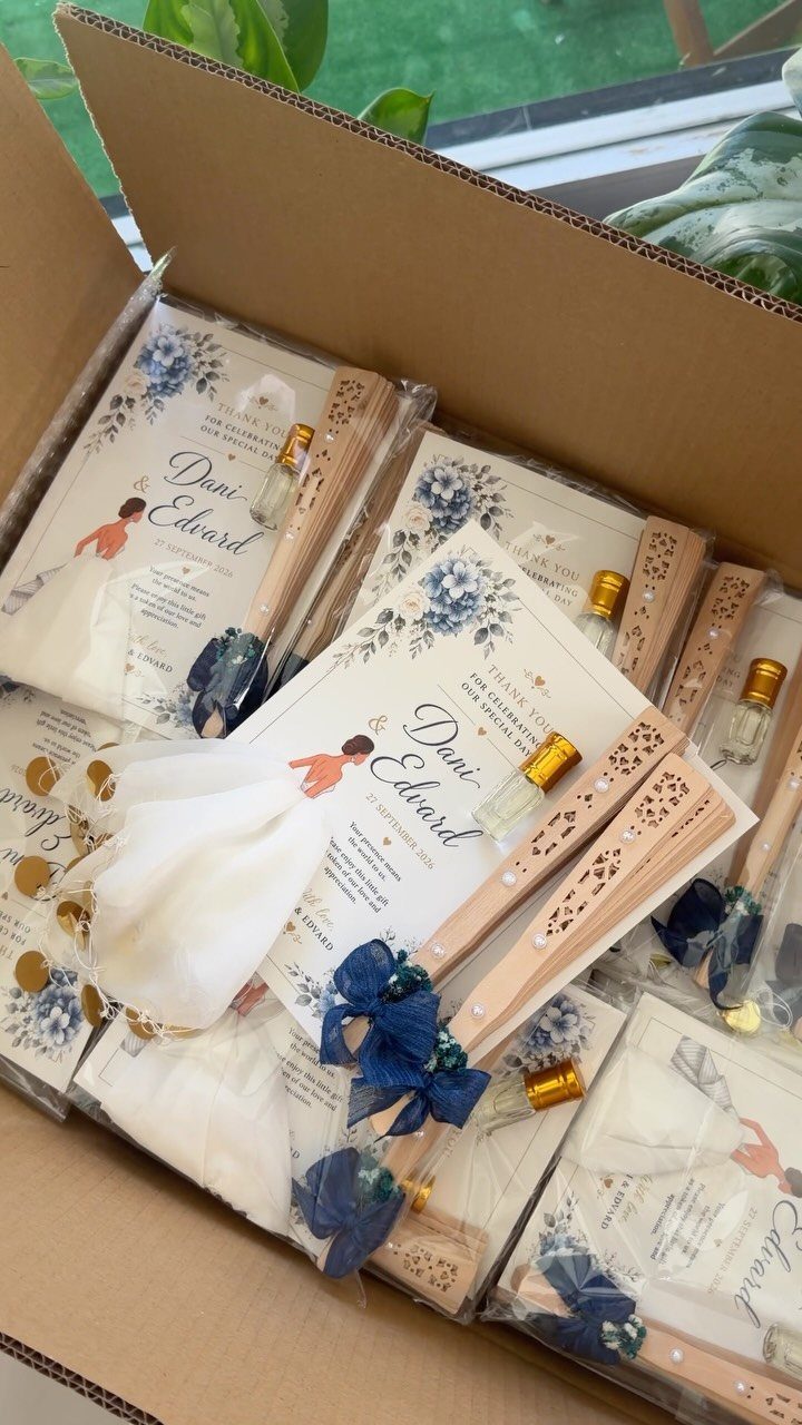 Wedding favor sets with perfume bottles, wooden fans, and floral cards in a box.