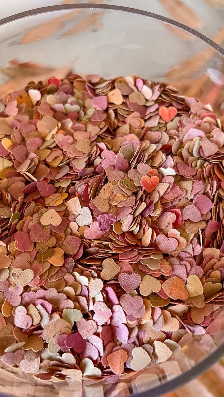 Heart-shaped confetti in pink and gold tones inside a clear glass bowl.