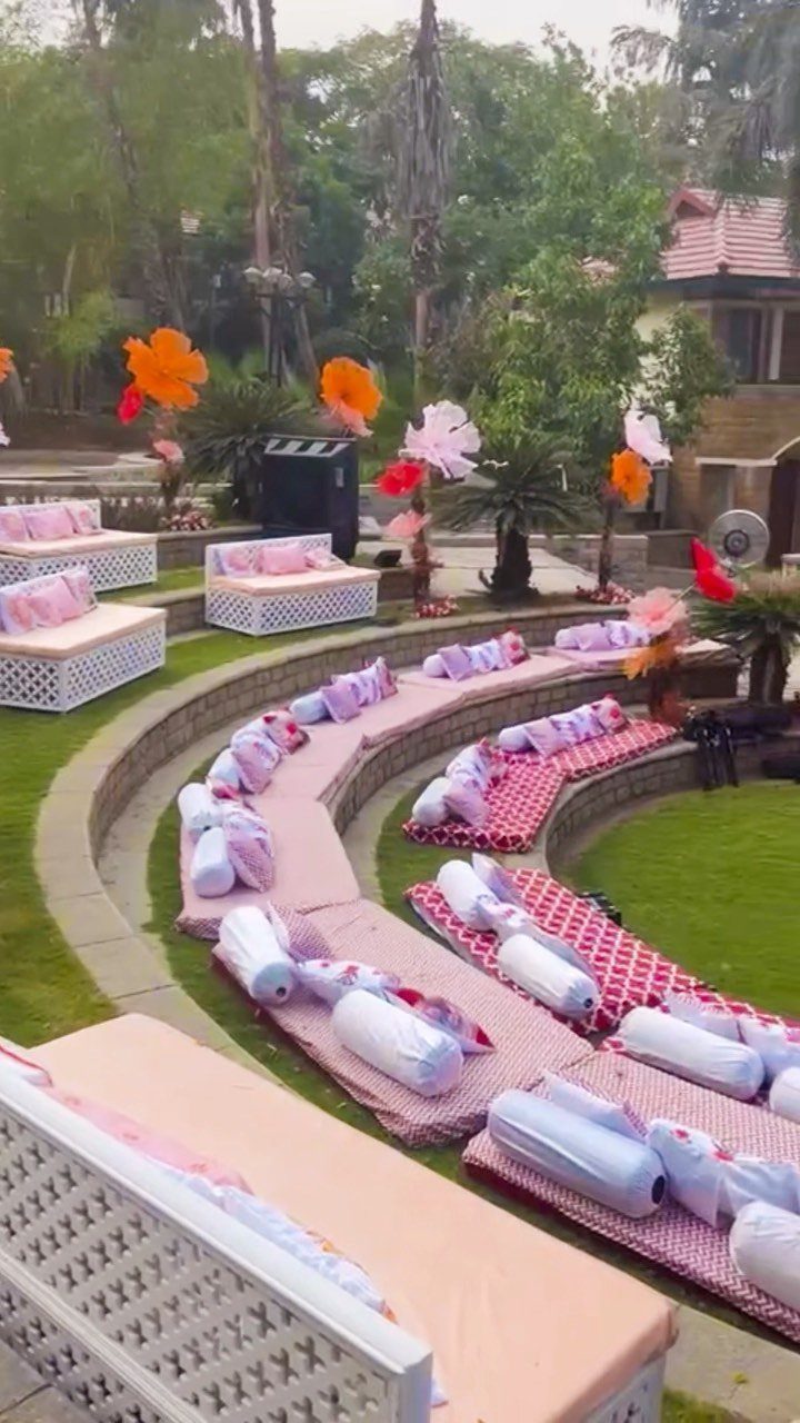 Curved stone tiers with checkered mats and pink cushions in a garden setting.