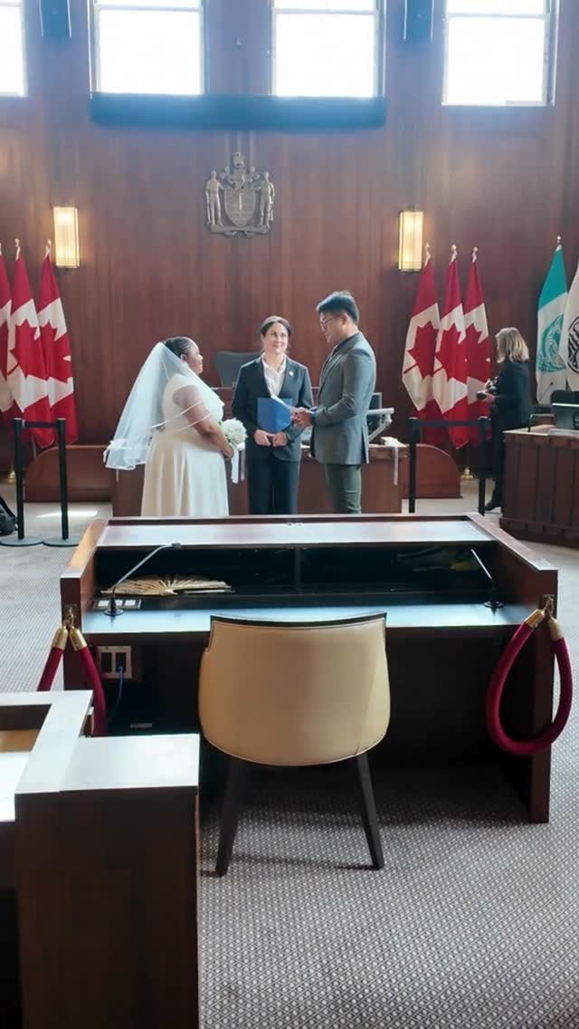 City Hall Wedding Ideas: 7 Ways to Plan the Day 3 Wedding couple standing before an officiant in a wood-paneled room with Canadian flags.