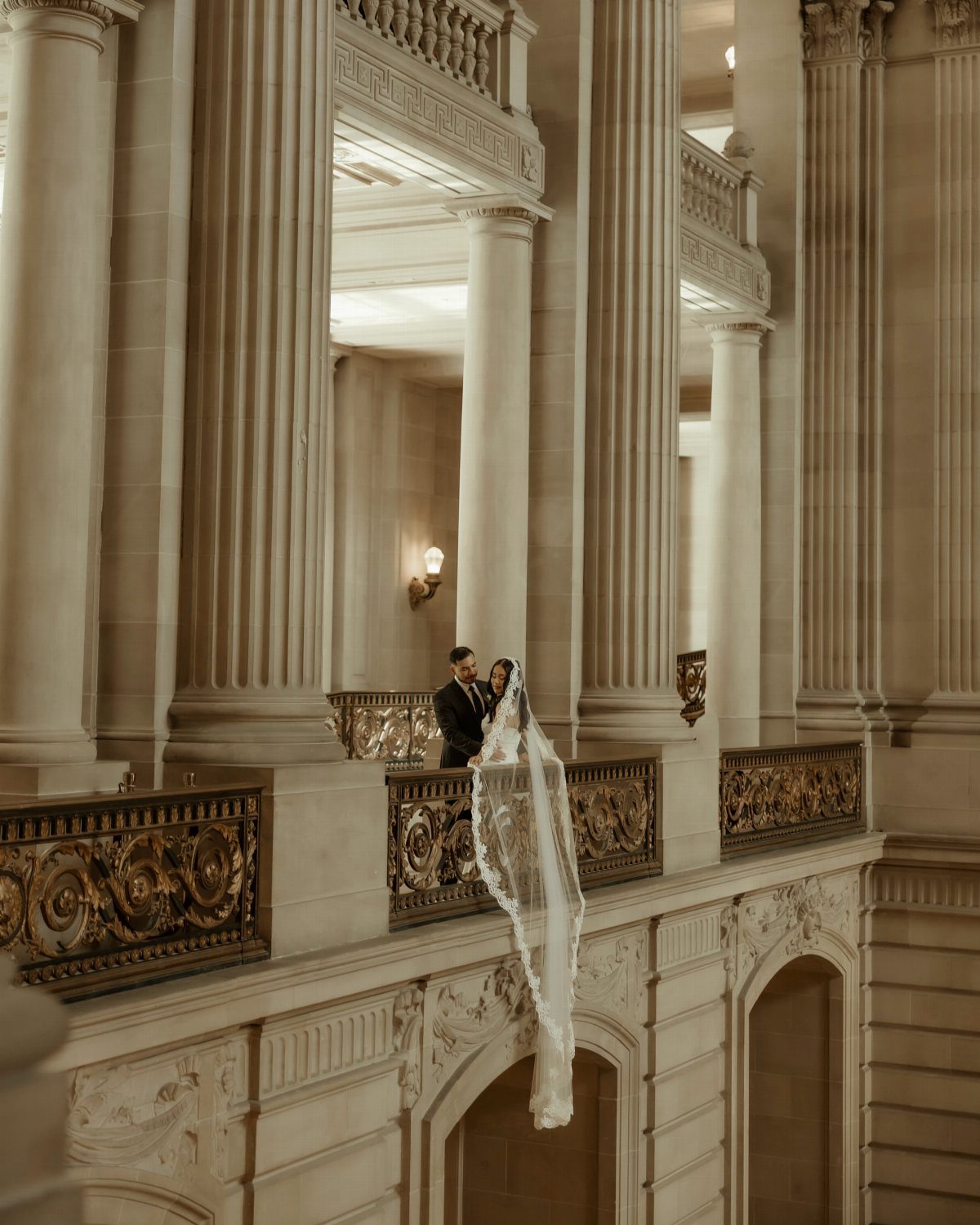 City Hall Wedding Ideas: 7 Ways to Plan the Day 7 Bride and groom posing on a balcony with columns in a grand hall.