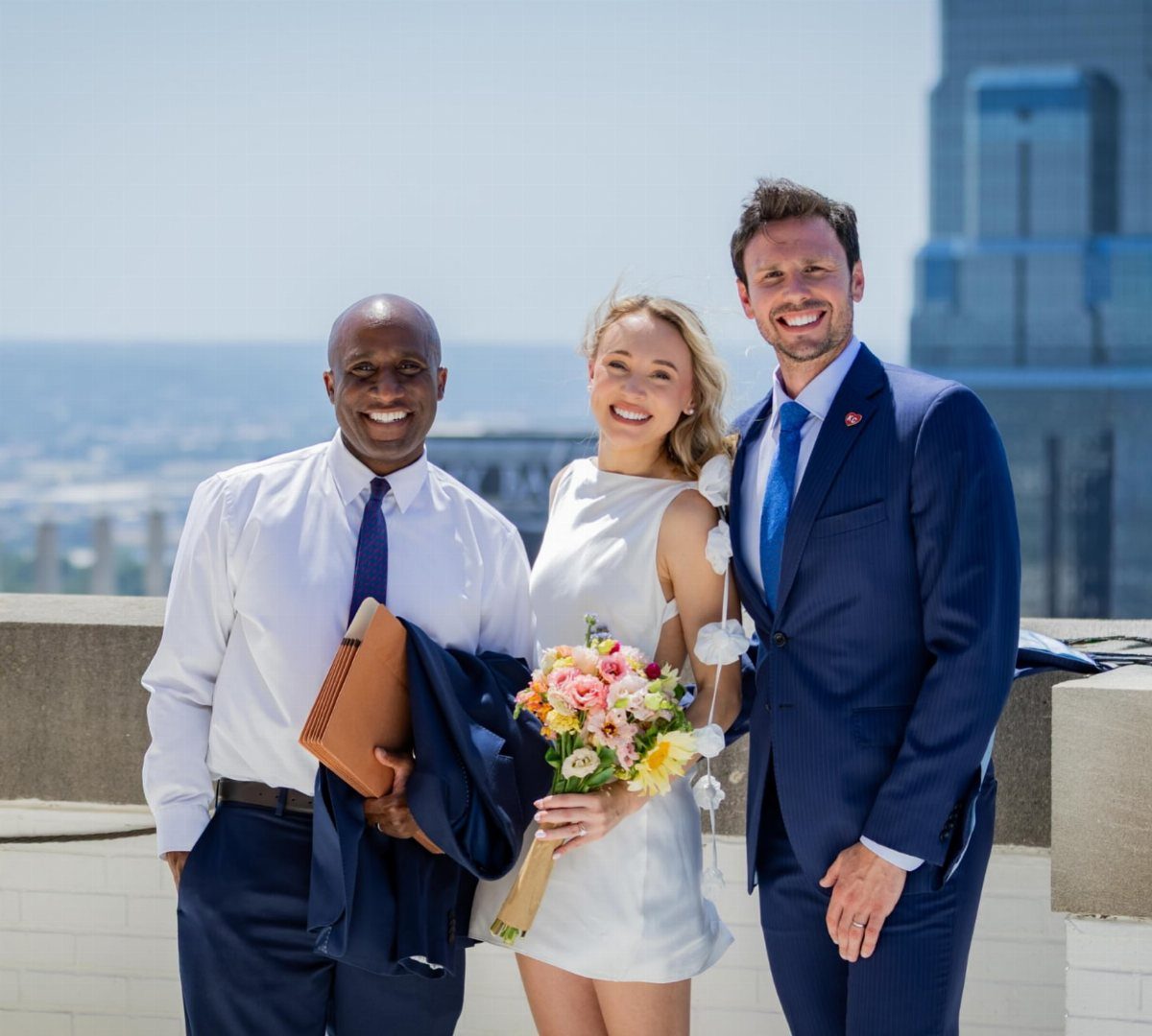 City Hall Wedding Ideas: 7 Ways to Plan the Day 5 Three people posing on a rooftop, including a bride with a colorful bouquet.