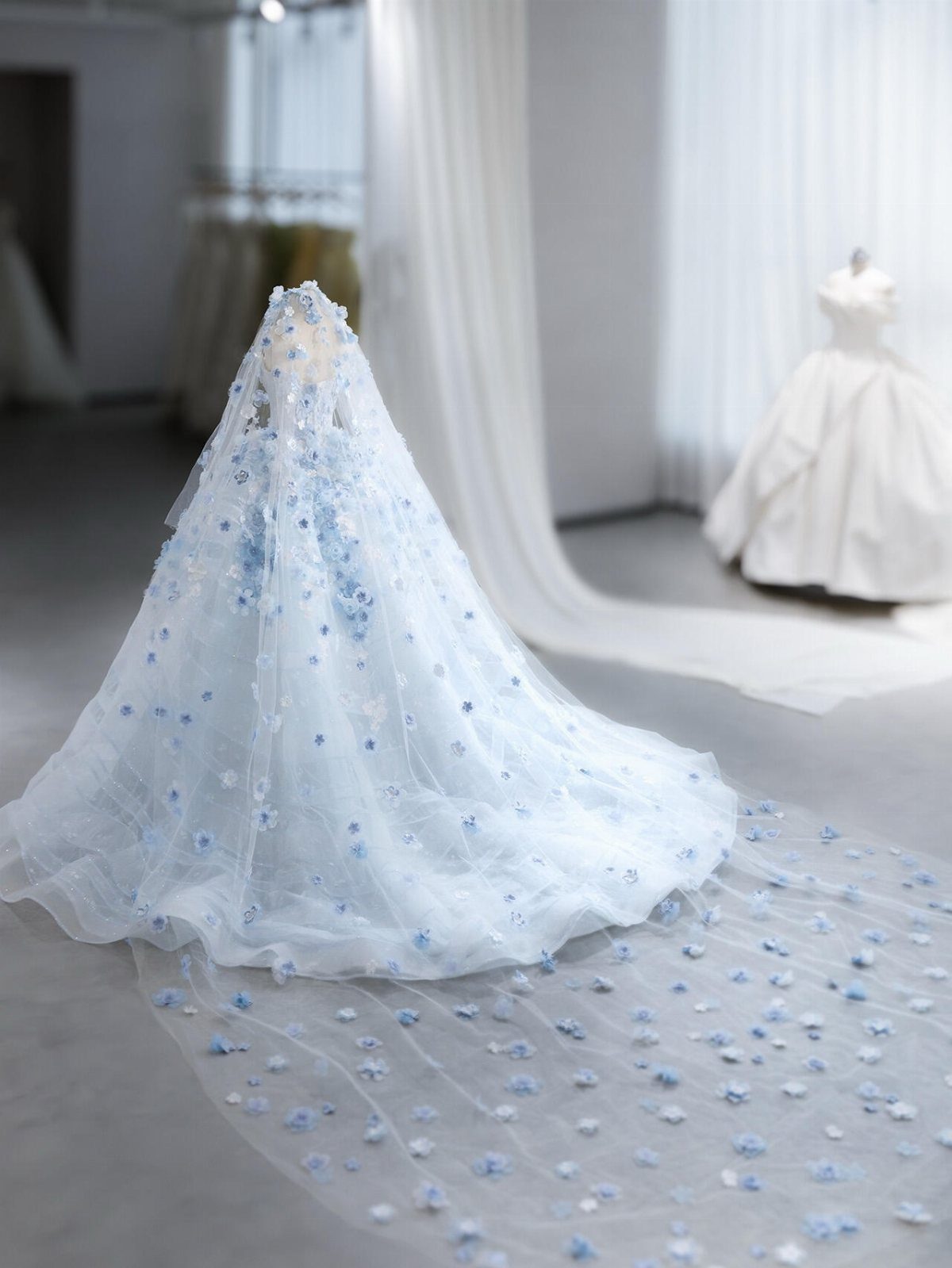 Light blue wedding dress with floral embroidery and a long flowing train.