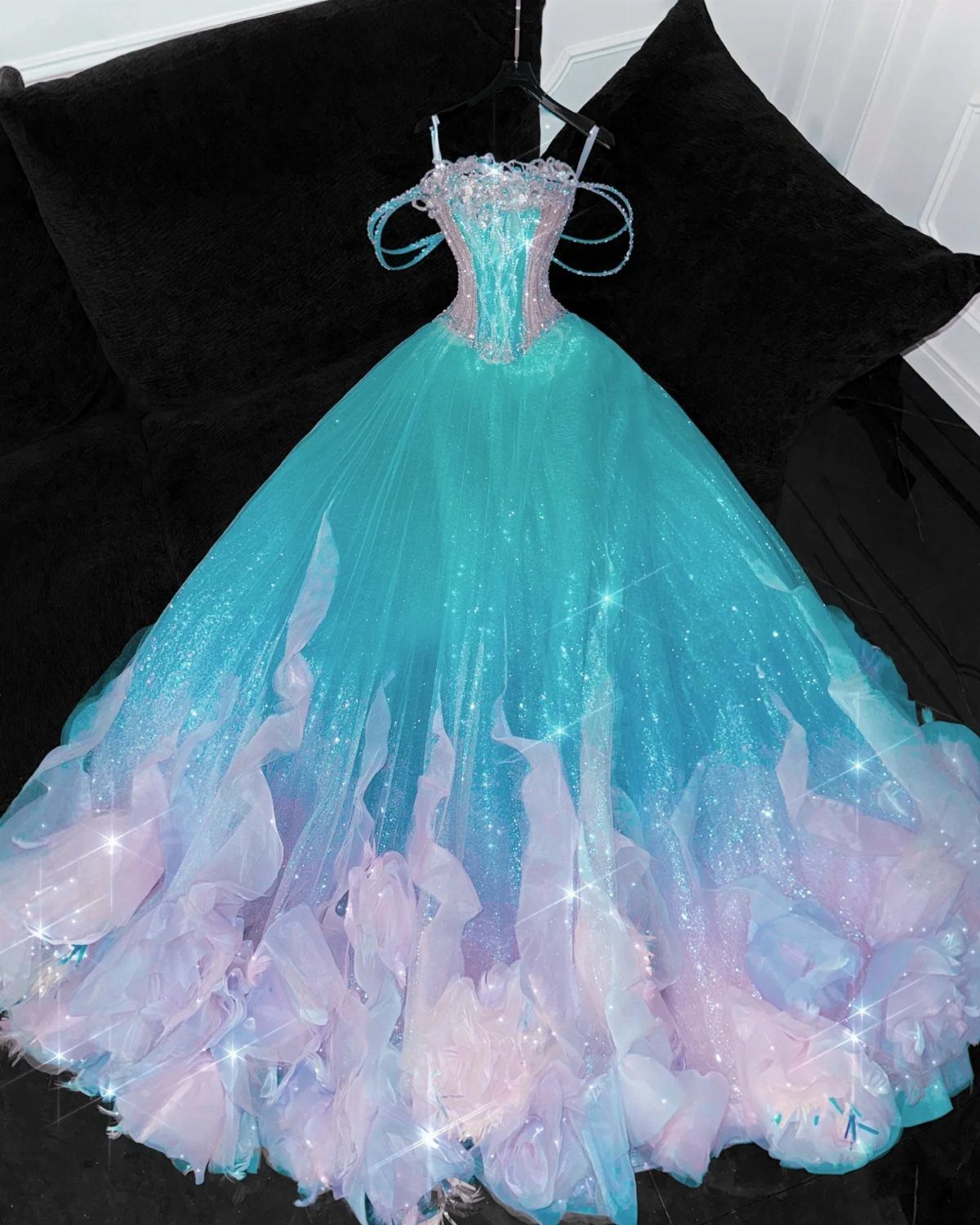 Turquoise and pink sparkling ball gown wedding dress hanging against a black background