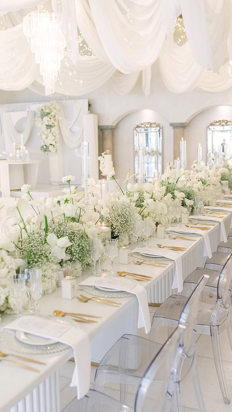 Colour Scheme for Wedding: 15 Ideas and Palettes 7 White wedding reception table with lush white flowers, gold cutlery, and clear acrylic chairs.
