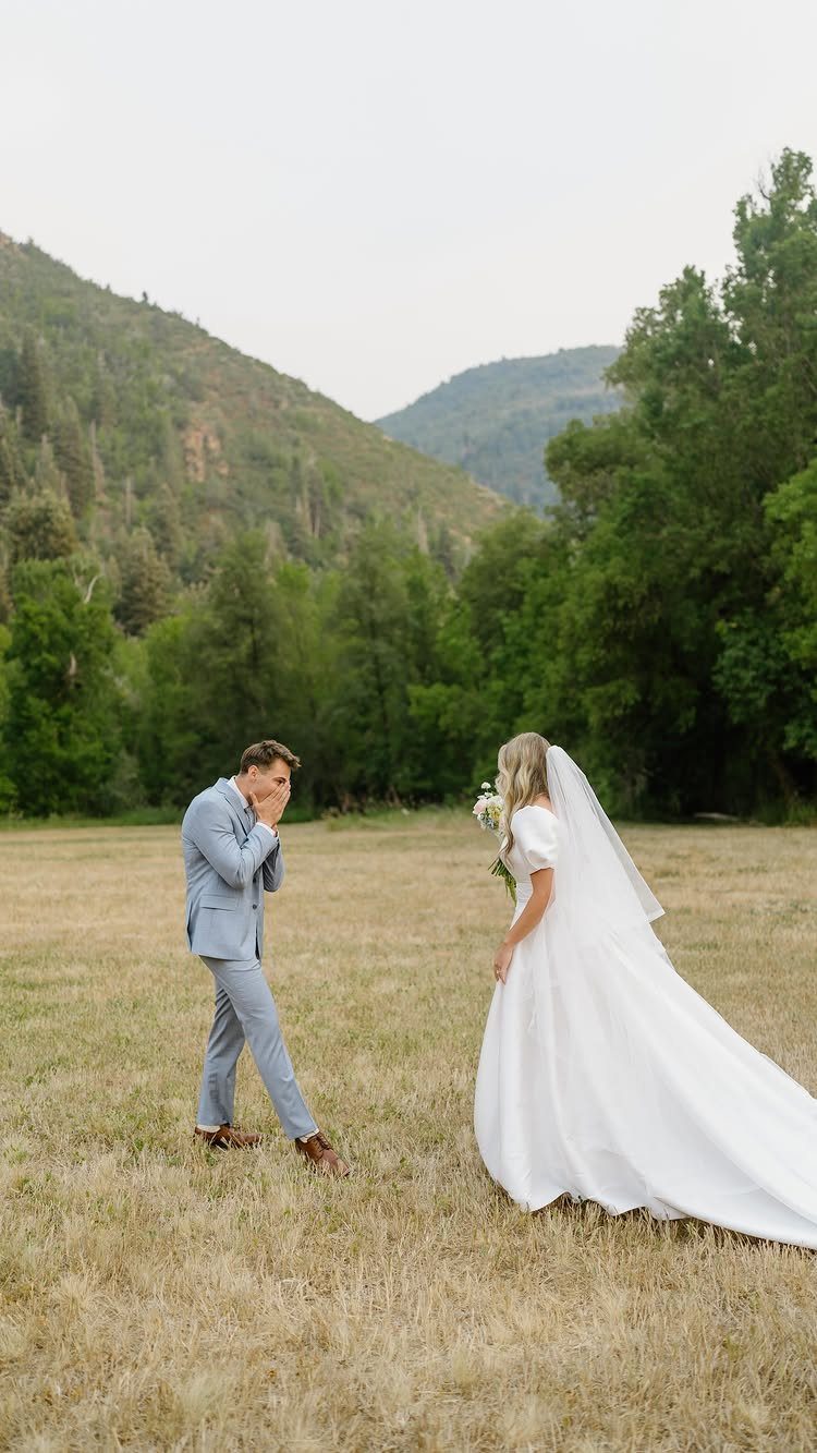 Groom in blue suit reacting with surprise to bride in white wedding dress.