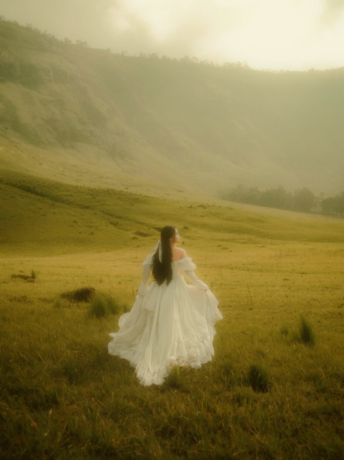Bride in a white flowy dress twirling in a golden misty mountain field