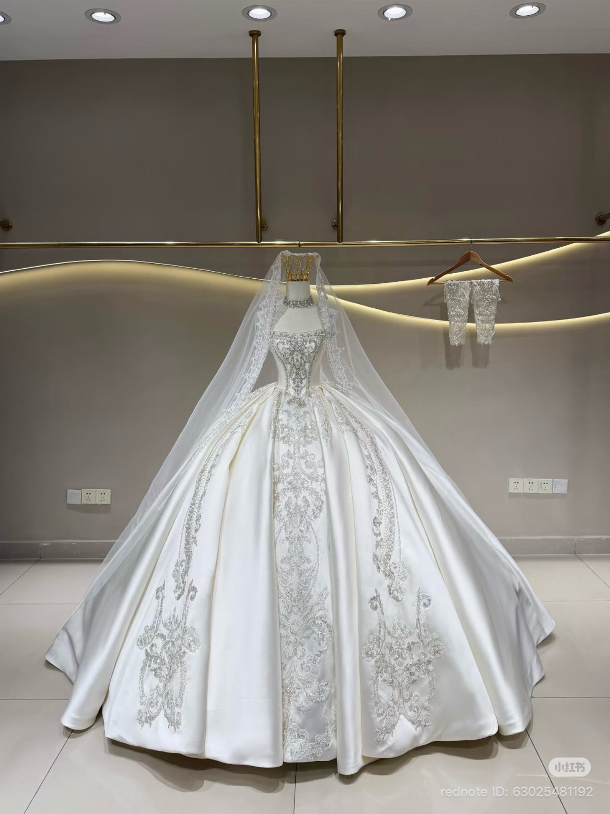 White ballgown wedding dress with silver embroidery and veil on a mannequin.