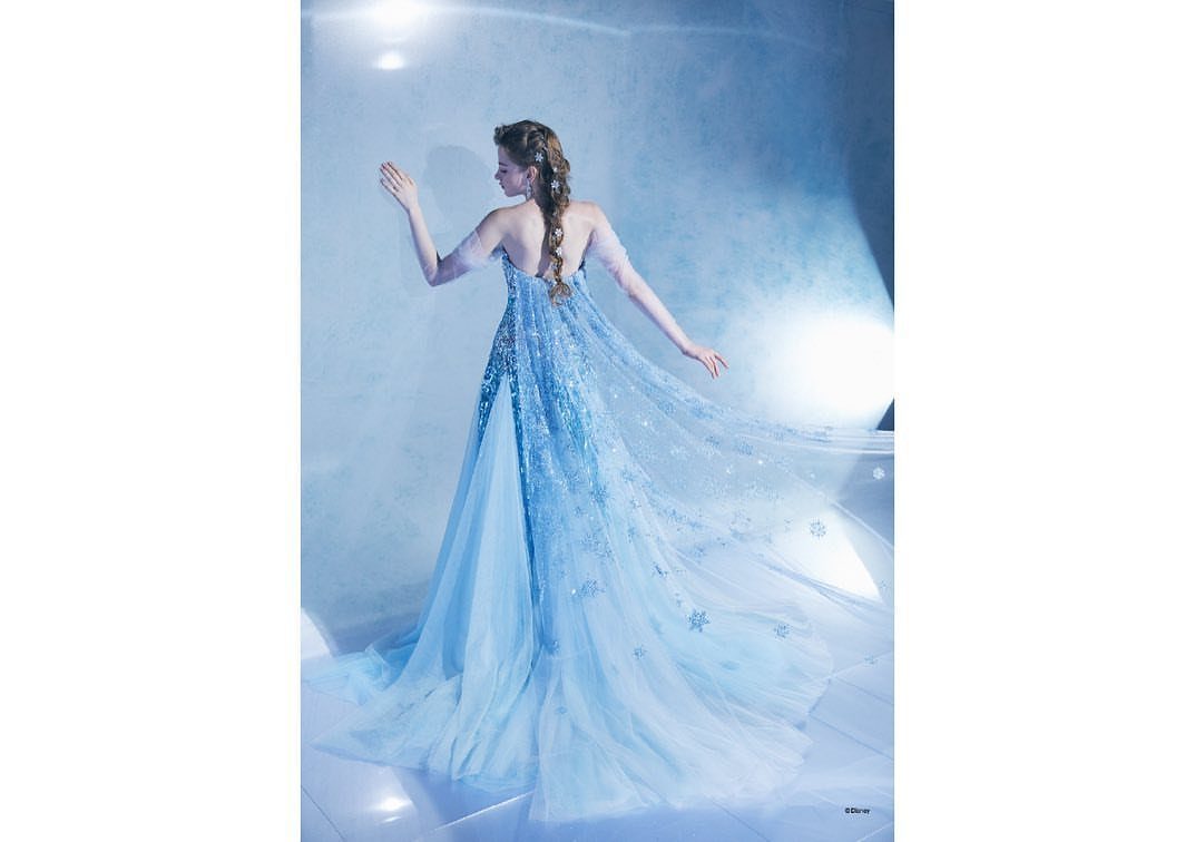 Woman in a sparkling light blue princess gown with a long flowing train.