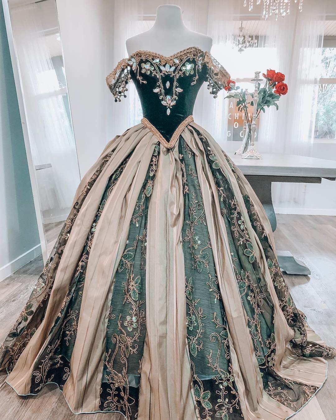 Ornate dark green and gold ball gown with velvet bodice on a mannequin