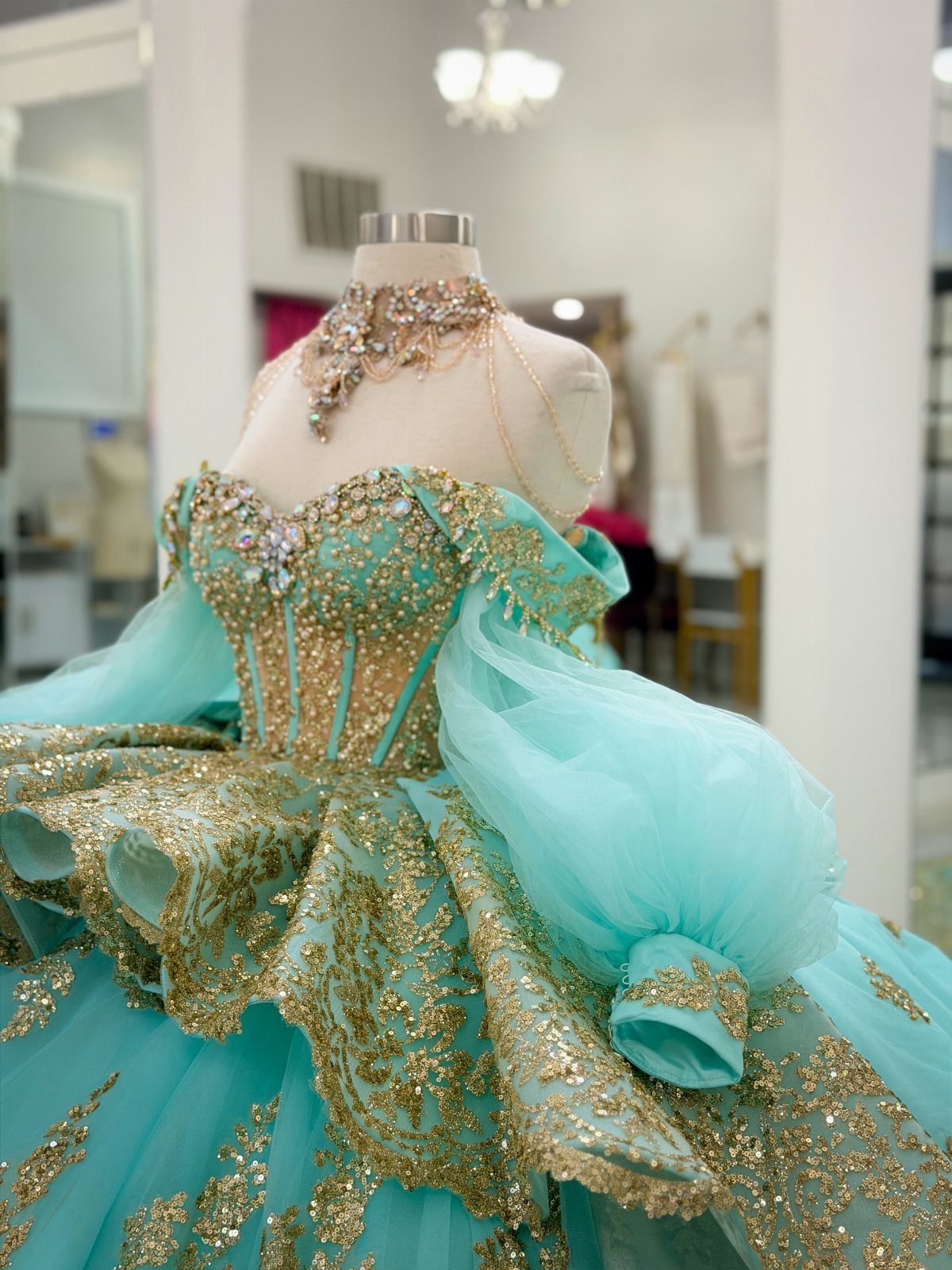 Turquoise ball gown with gold glitter embroidery and tulle on a mannequin