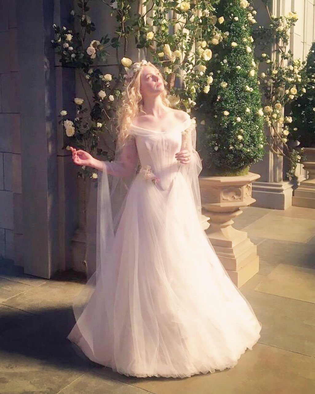 Woman in a voluminous white tulle wedding gown and floral crown in a rose garden