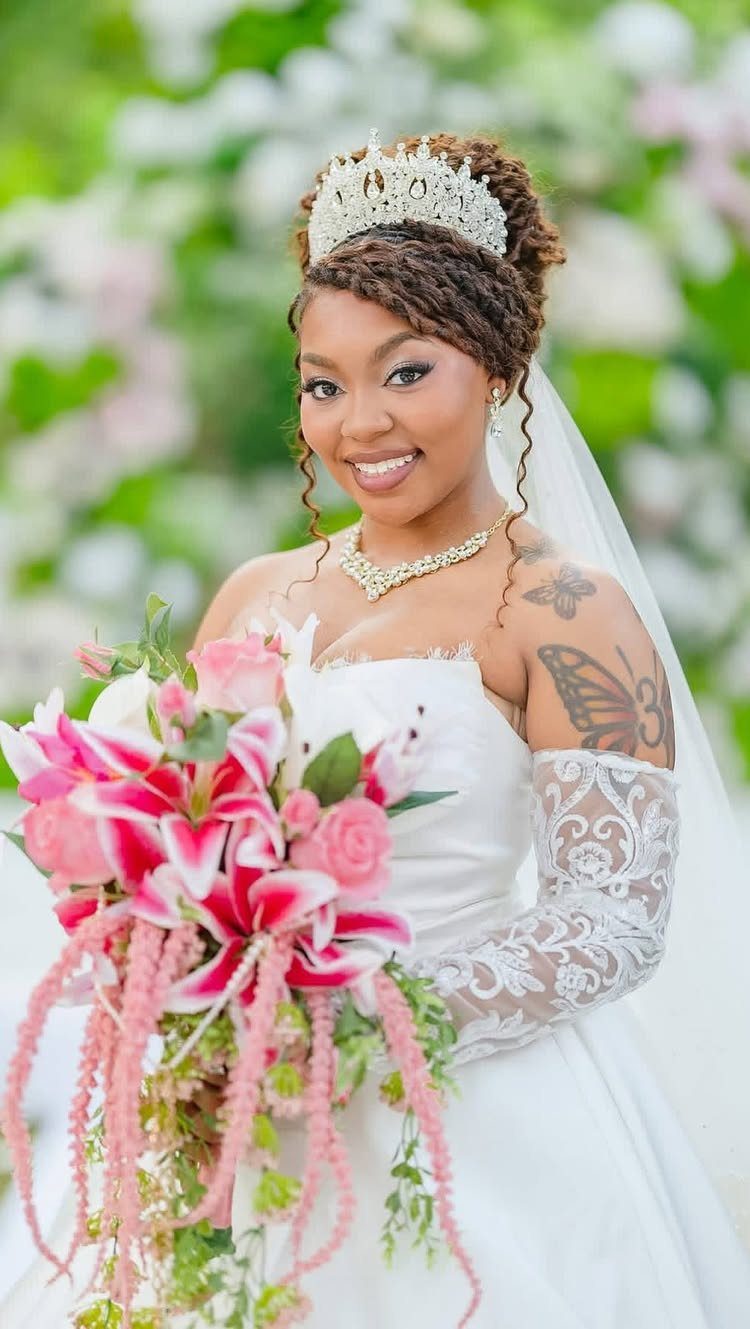 Bride in a white wedding dress and tiara holding a pink lily bouquet.