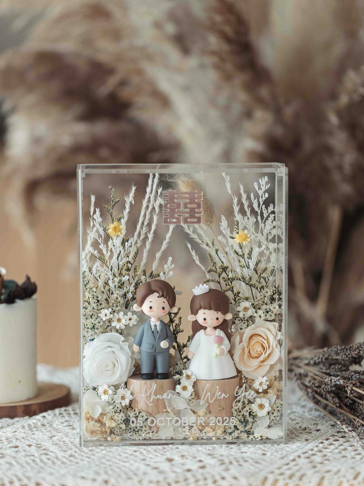 Acrylic wedding keepsake block with bride and groom figurines and dried flowers.