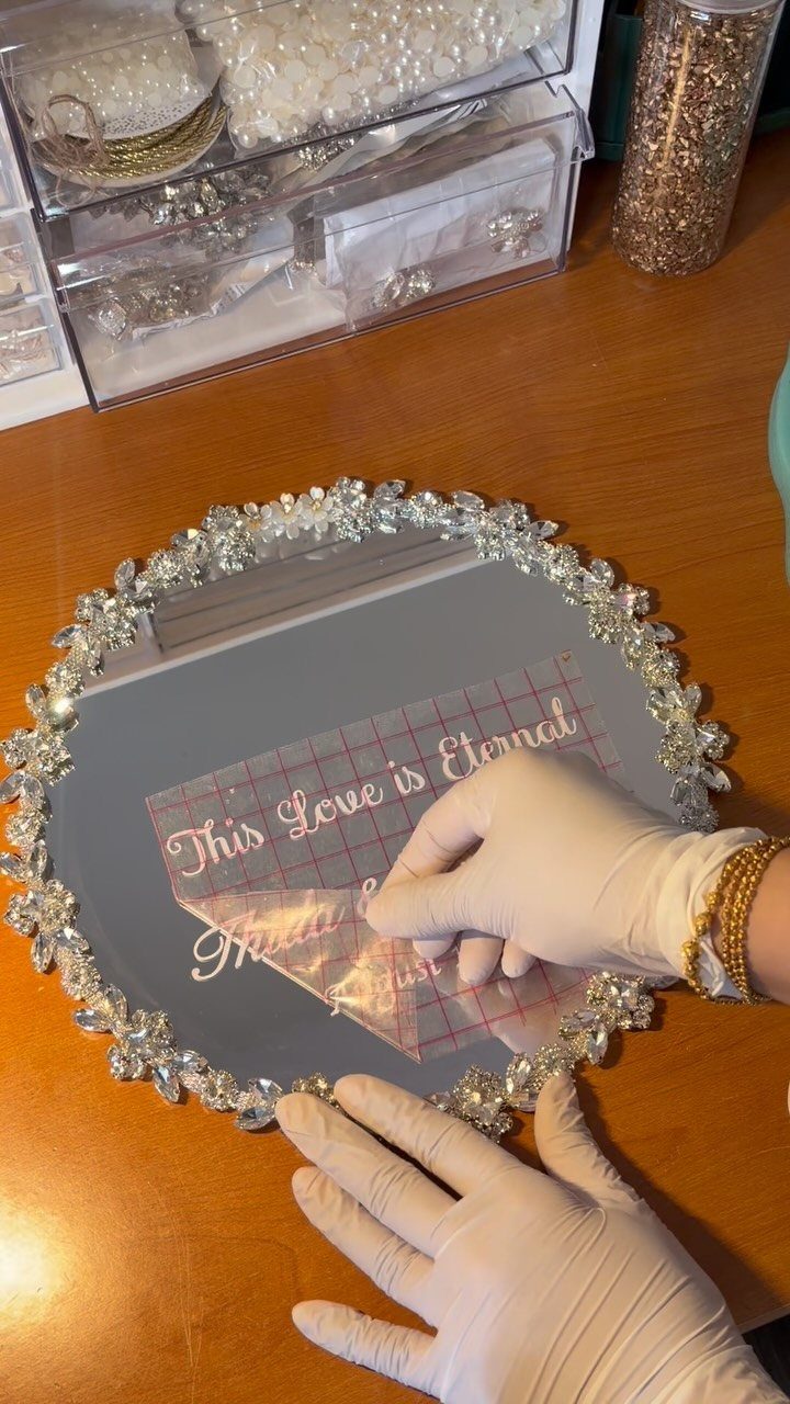 Person applying a romantic text decal to a crystal-bordered circular mirror.