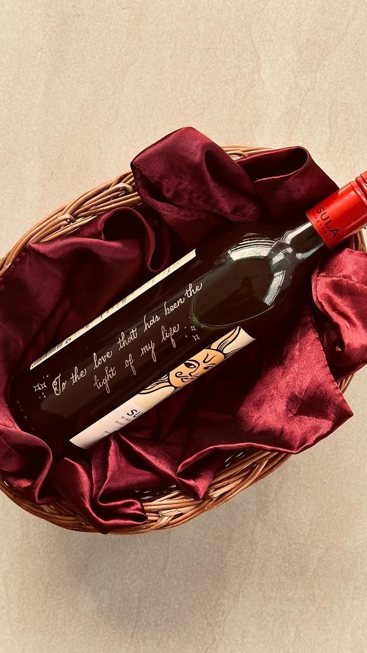 Personalized wine bottle with handwritten message resting in a red satin lined basket