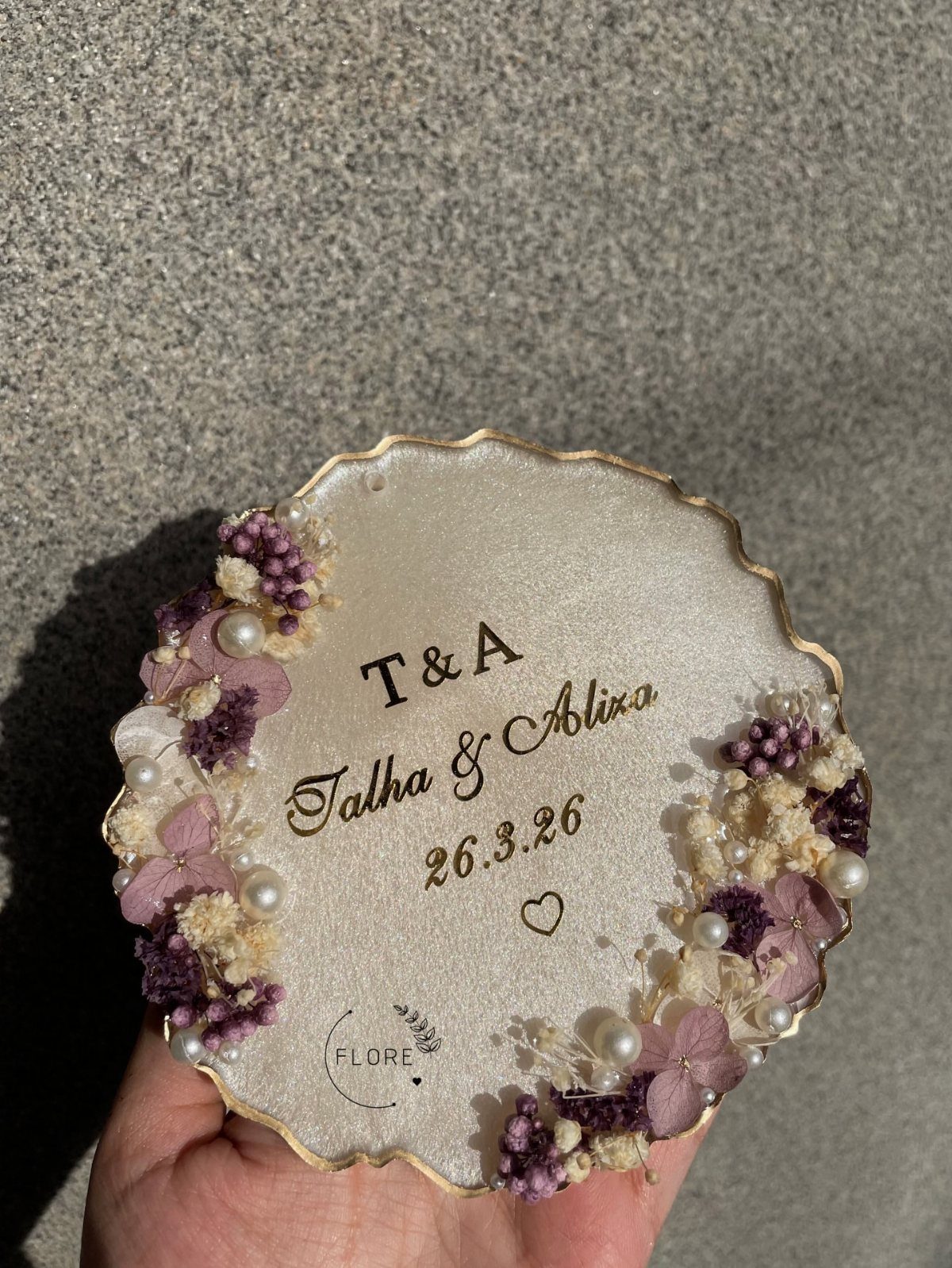 Resin coaster with dried purple flowers and personalized wedding names and date.