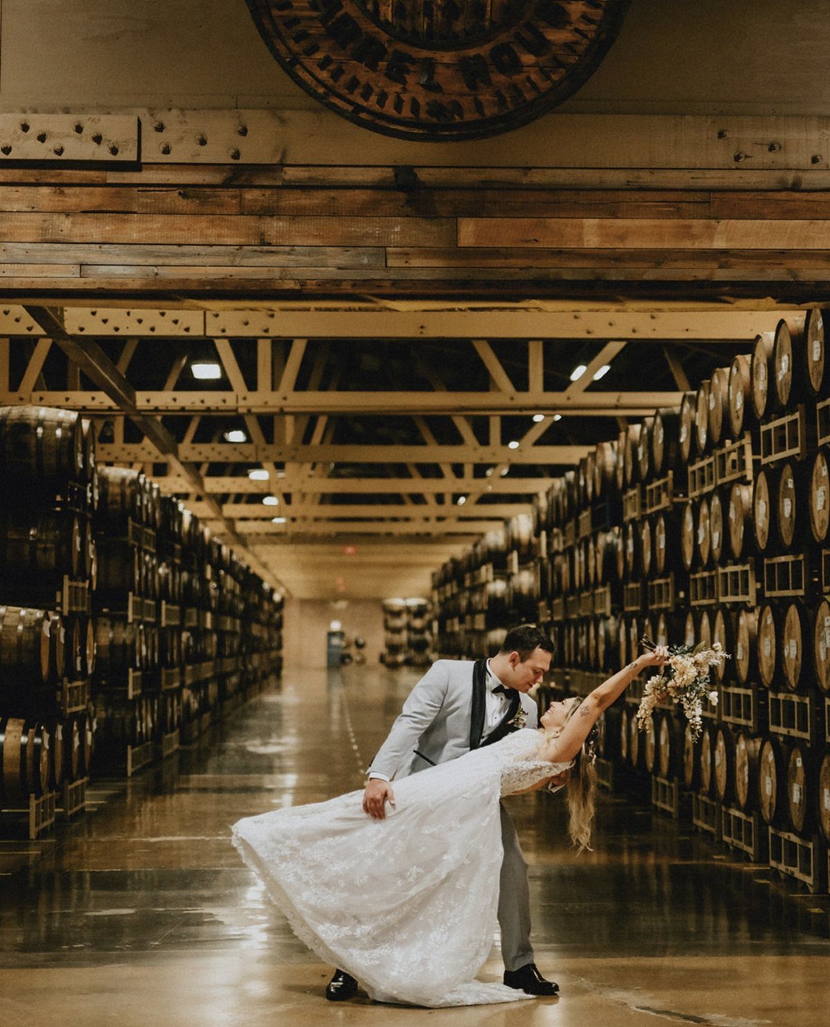 Dream Wedding Venue Ideas: 11 Places to Say I Do 8 Bride and groom kissing in a brewery aisle lined with wooden barrels.