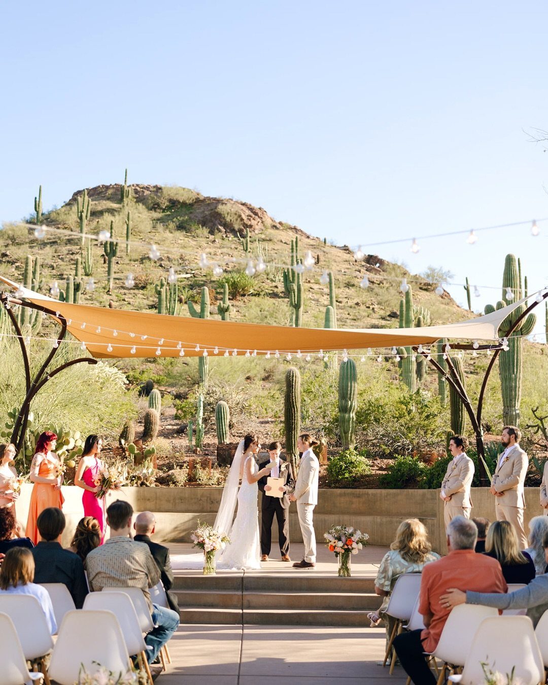 Dream Wedding Venue Ideas: 11 Places to Say I Do 2 Wedding ceremony in a desert landscape with saguaro cacti and a tan fabric canopy.