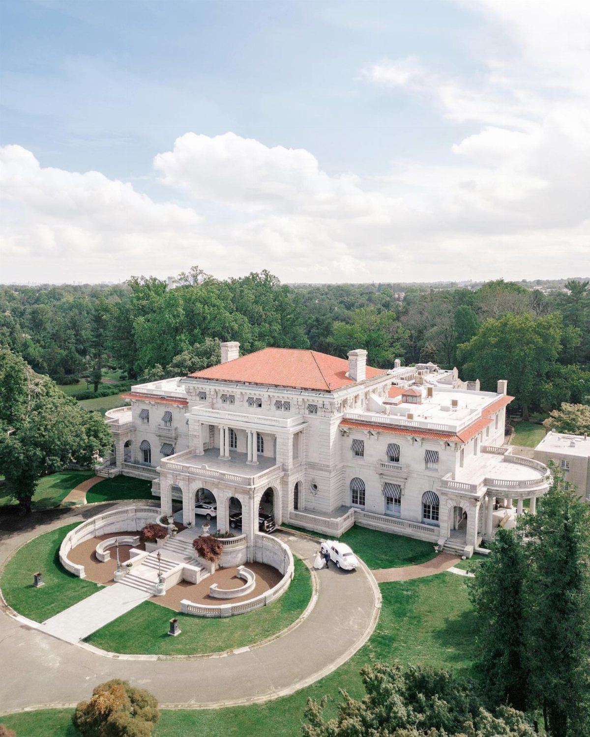 Dream Wedding Venue Ideas: 11 Places to Say I Do 10 Large white neoclassical mansion with red roof and circular driveway surrounded by green trees.