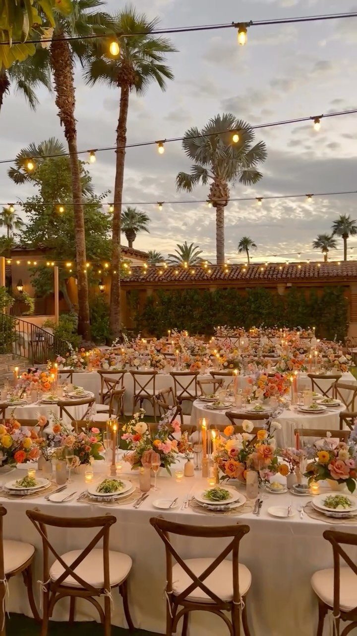 Dream Wedding Venue Ideas: 11 Places to Say I Do 5 Outdoor wedding reception with white tables, floral arrangements, and palm trees under string lights.