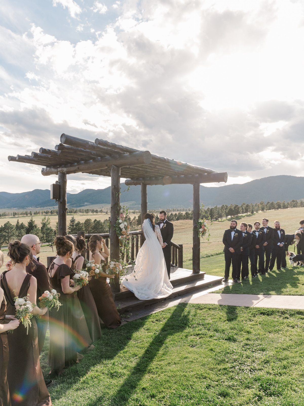 Dream Wedding Venue Ideas: 11 Places to Say I Do 3 Wedding couple under a rustic timber pergola with mountains in the background.