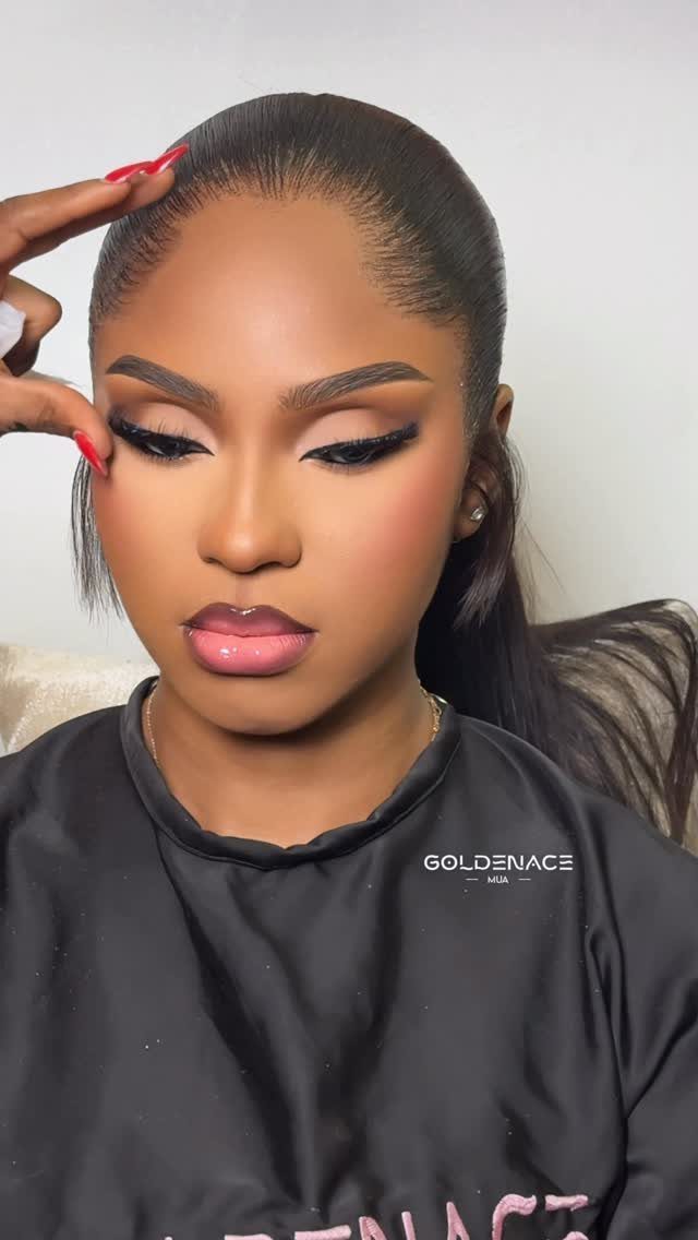 Woman with dramatic dark eye makeup and glossy lips posing for a portrait.