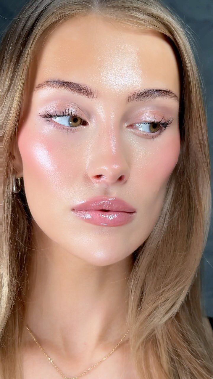 Woman with luminous, glowing skin, pink blush, and shimmering makeup for a wedding guest.