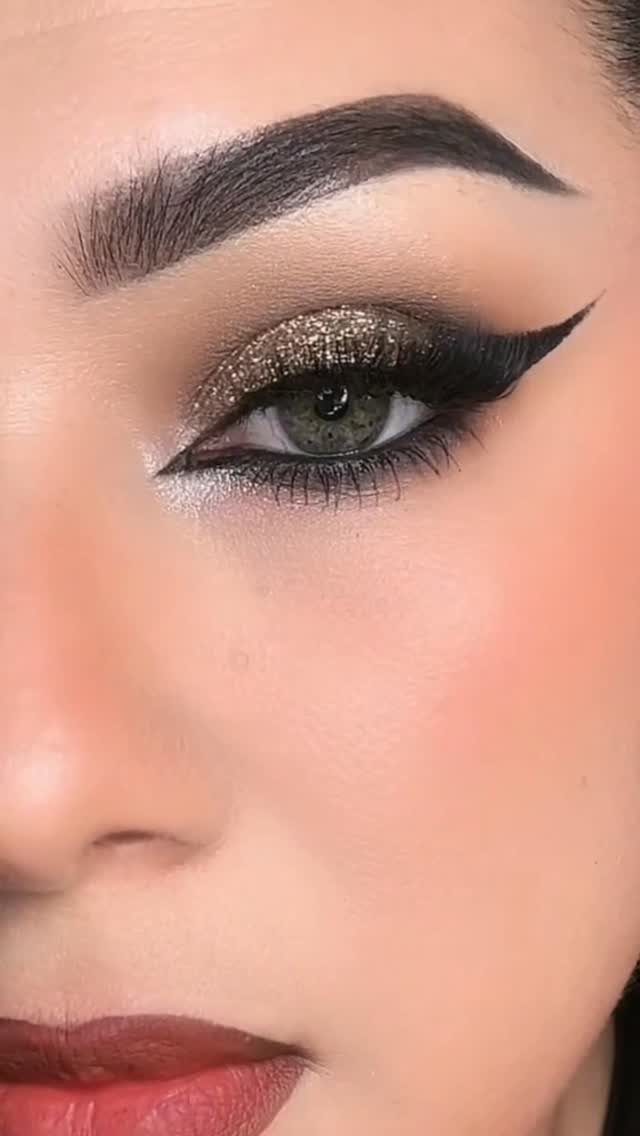 Eye with gold glitter eyeshadow and sharp black winged eyeliner on a woman