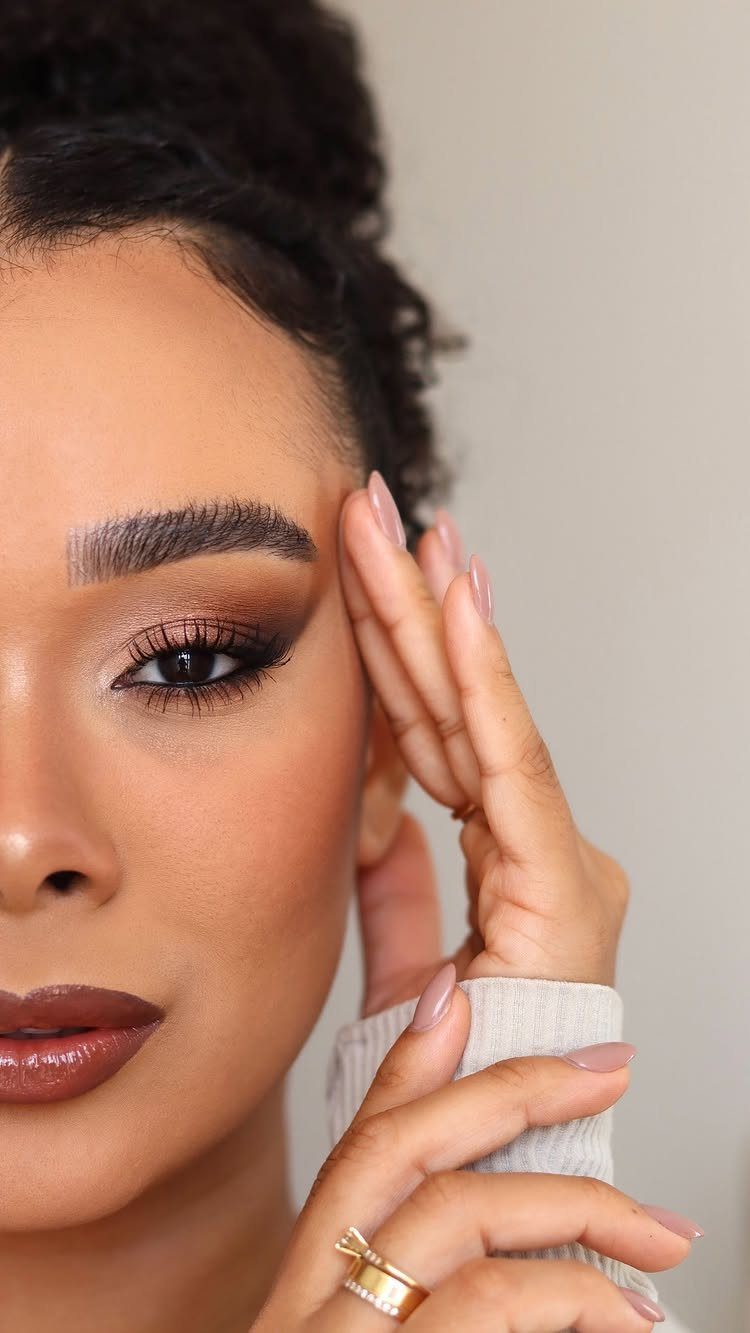 Woman with brown and gold eye makeup and brown lipstick posing for a portrait