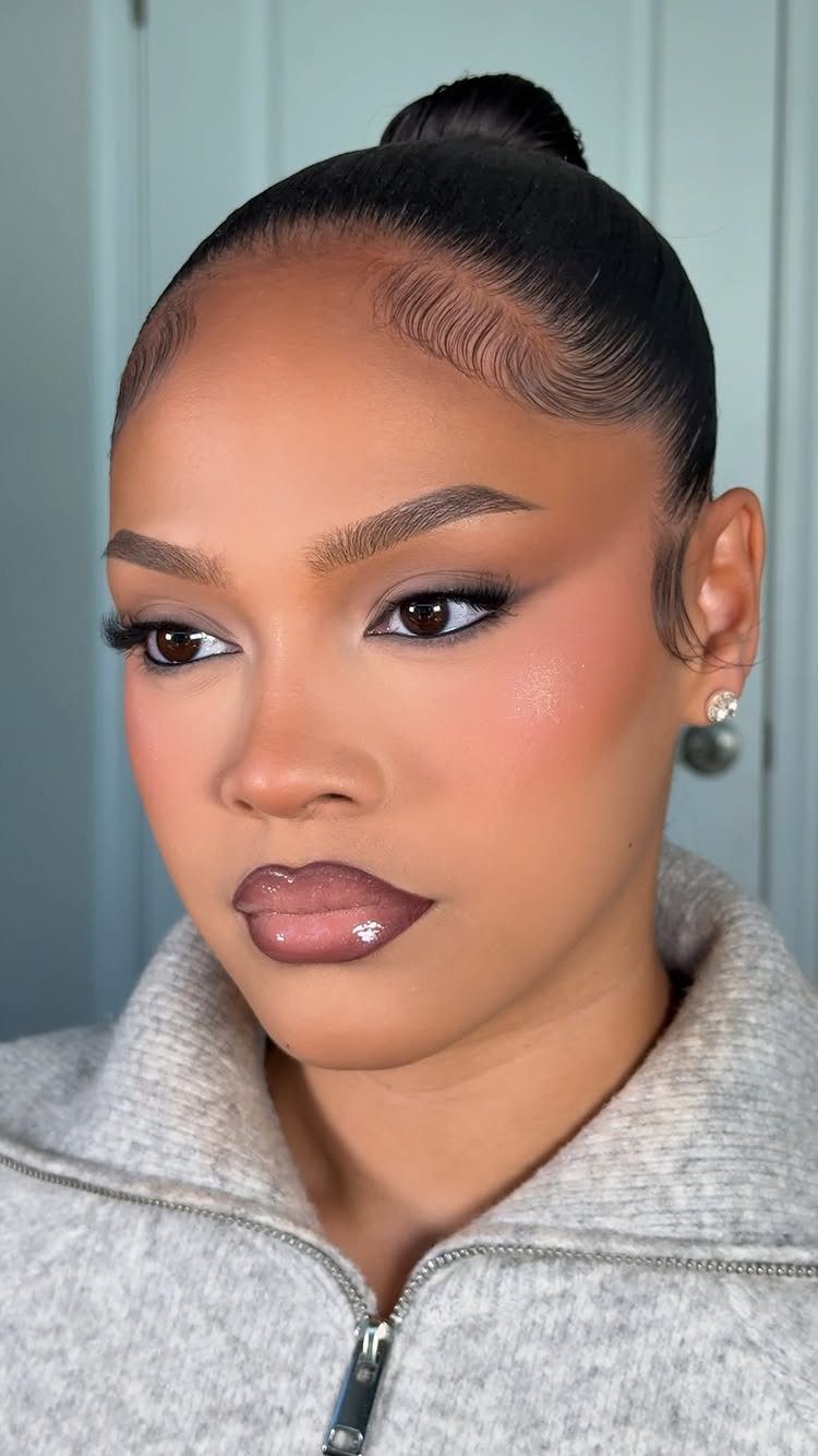 Woman with soft glam makeup, brown eyeshadow, and glossy lips posing for a portrait.