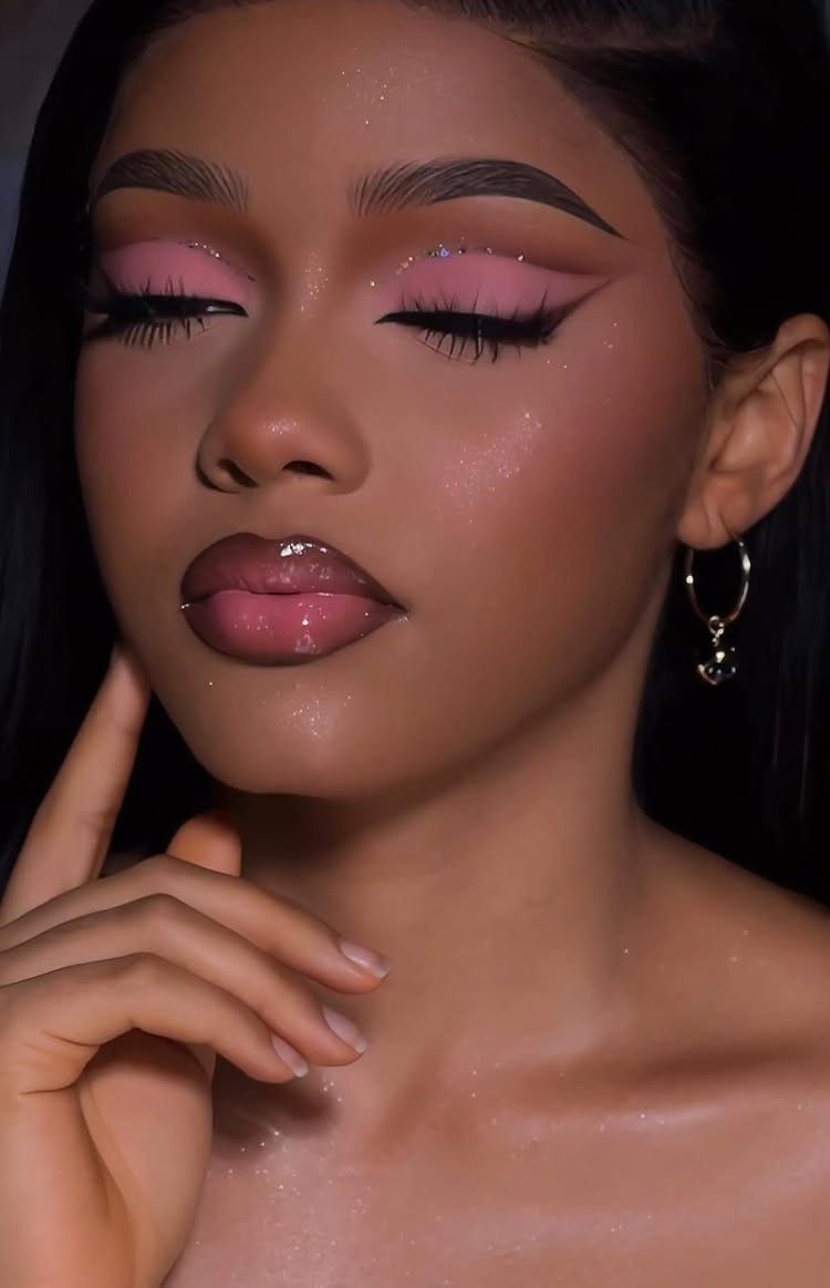 Woman with pink eye makeup and winged eyeliner posing for a close-up portrait.