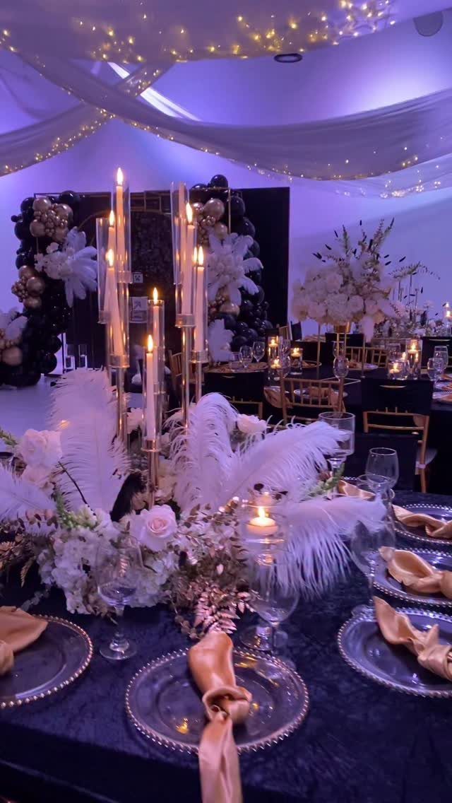 Elegant wedding table setting with gold plates, white flowers, and tall lit candelabras.