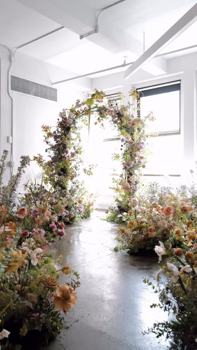 Floral archway with colorful blooms creating a whimsical path in a bright room.
