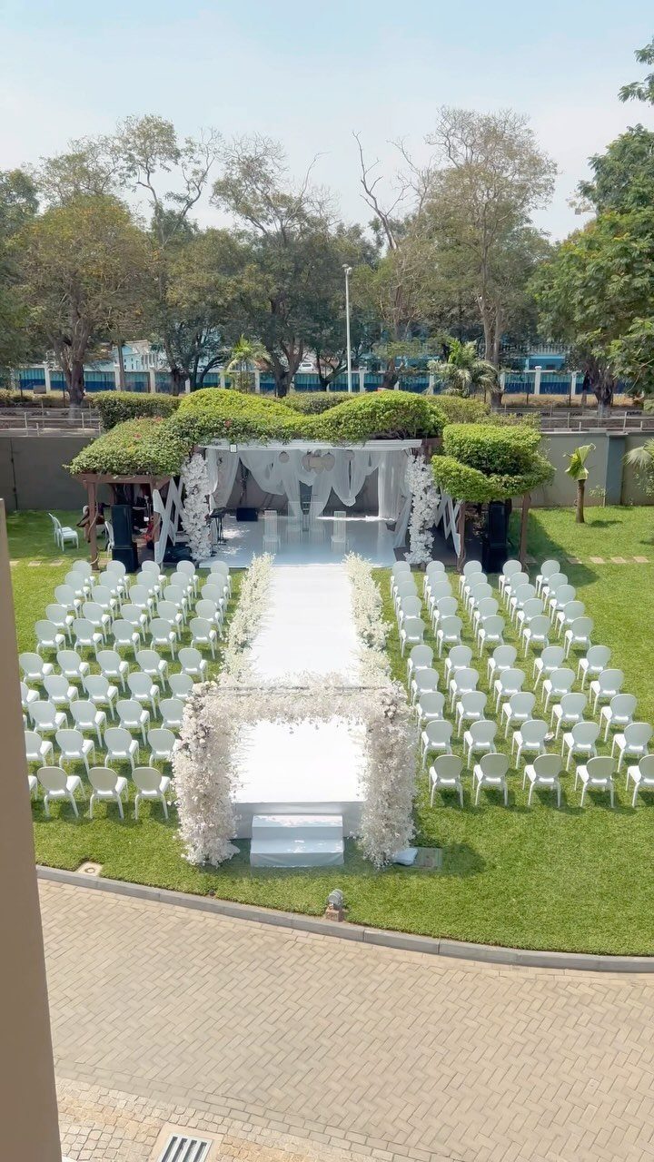 Outdoor wedding ceremony setup with white chairs and a floral altar in a garden