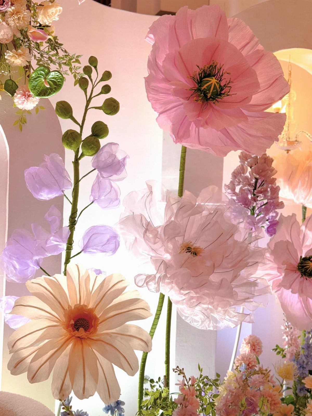 Oversized pink and white artificial flowers in a whimsical, fairytale-style floral arrangement.