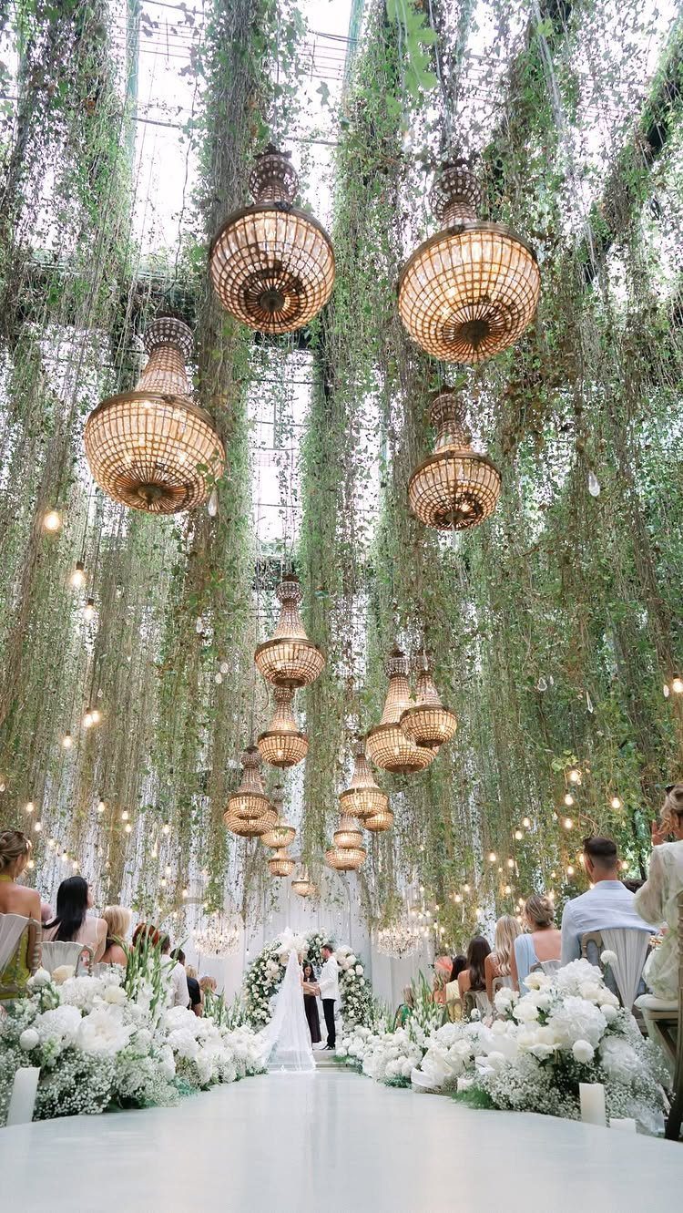 Fantasy Wedding Venue Ideas: 11 Storybook Settings 11 Ornate gold chandeliers and hanging greenery over a white wedding table with floral arrangements